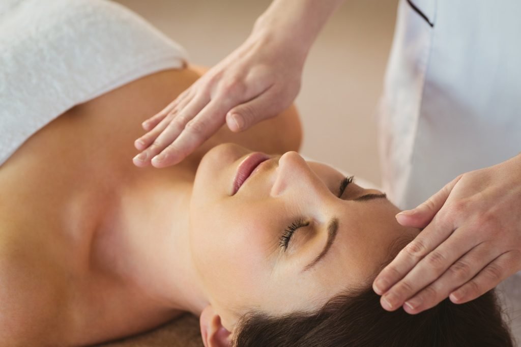 Young woman having a reiki treatment in therapy room